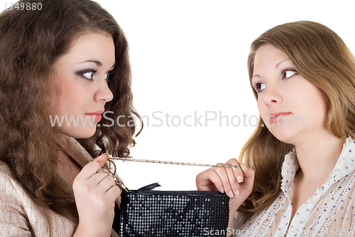 Image of Two beautiful girls and one handbag. Isolated