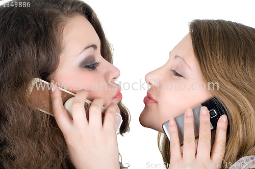 Image of Two beautiful girls with phones. Isolated on white