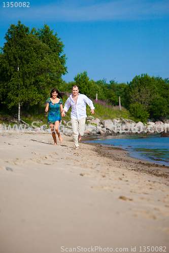 Image of Enamored couple running along the coast of sea