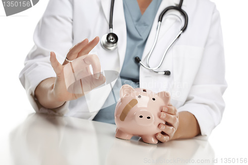 Image of Doctor Gives Okay Sign Behind Piggy Bank