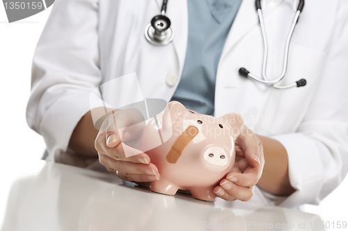 Image of Doctor Holding Caring Hands on a Piggy Bank with Bandage