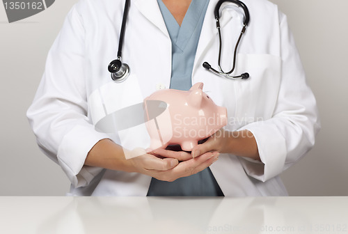 Image of Doctor with Stethoscope Holding Piggy Bank Abstract