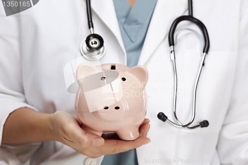 Image of Doctor with Stethoscope Holding Piggy Bank Abstract