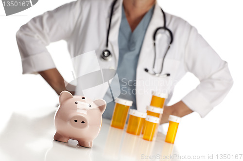 Image of Doctor Standing Behind Medicine Bottles and Piggy Bank