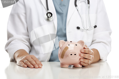 Image of Doctor Holding Caring Hand on a Piggy Bank with Bandage