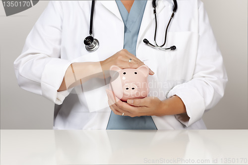 Image of Doctor with Stethoscope Holding Piggy Bank Abstract