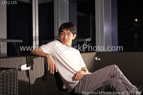 Image of Man sit on a bench while relaxing at a pub. 