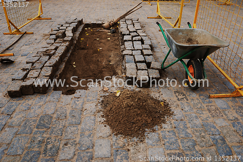 Image of stones, a wheelbarrow, and tools for paving 