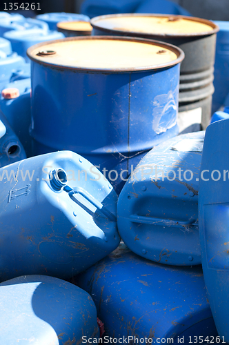 Image of Old colored oil barrels and blue canisters