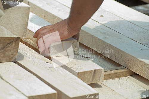 Image of Worker moves a wooden beam
