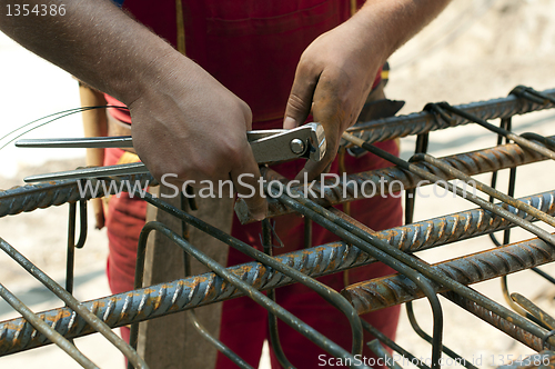 Image of Construction worker ties reinforcing steel