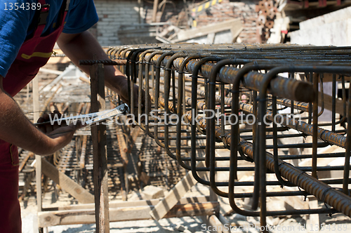 Image of Construction worker ties reinforcing steel