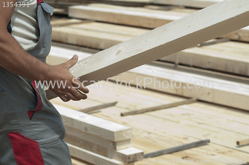 Image of Worker moves a wooden beam