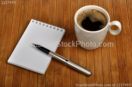 Image of notebook with a pen and a cup of coffee