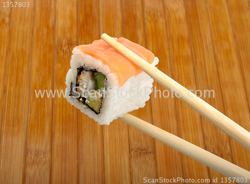 Image of sushi in wooden chopsticks