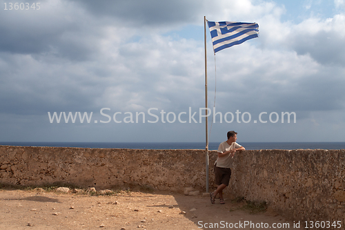 Image of  youth on stone castle under the greece flag