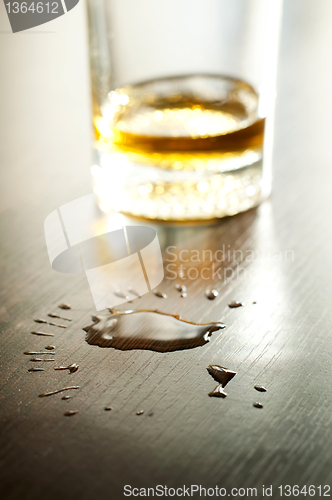 Image of Glass with whiskey and drops on the table