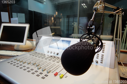 Image of mic in front of the control panel in broadcasting studio 