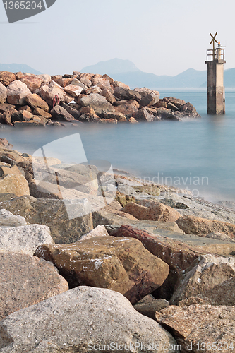 Image of Lighthouse on a Rocky Breakwall: A small lighthouse warns of a r