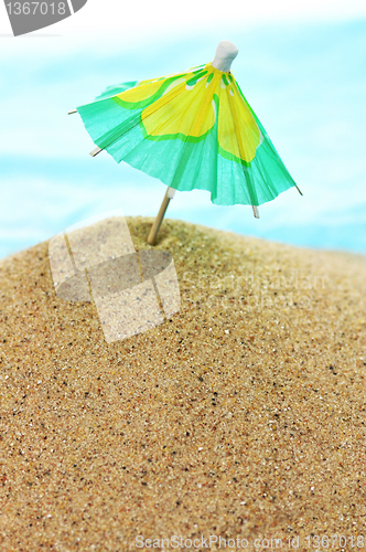 Image of cocktail umbrella on sand