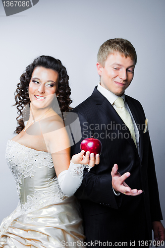 Image of bride offering a red apple to doubting groom