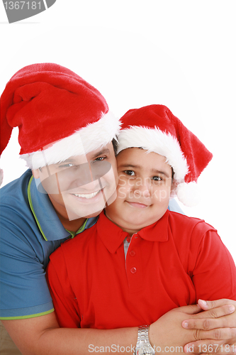 Image of Happy father and son with Christmas hats look to the camera