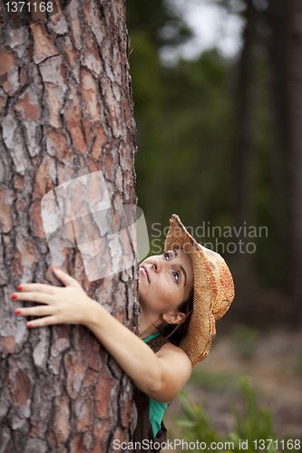 Image of Young woman embracing a tree