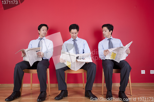 Image of Three businessman reading a newspaper