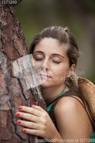 Image of Young woman embracing a tree