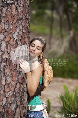 Image of Young woman embracing a tree