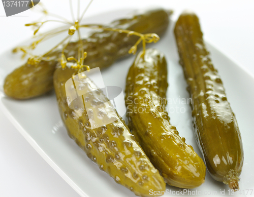 Image of dill pickles on a white dish 