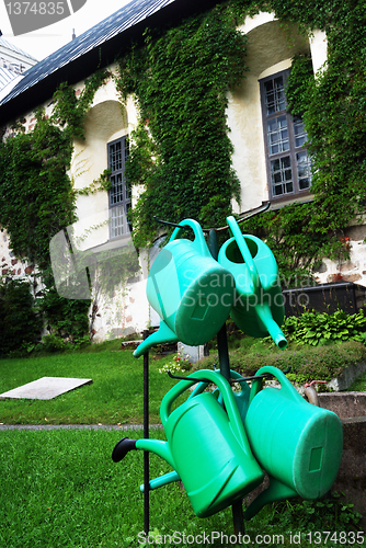 Image of four green watering can in the churchyard