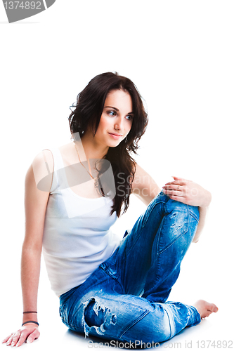 Image of pretty woman in blue jeans sitting on white floor