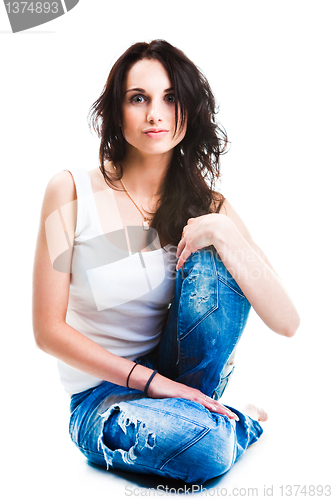 Image of pretty woman in blue jeans sitting on white floor