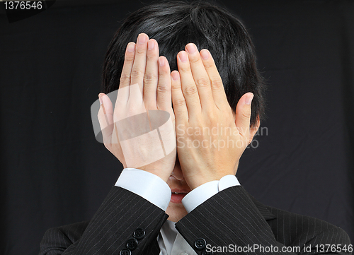 Image of businessman covering his face by hands 