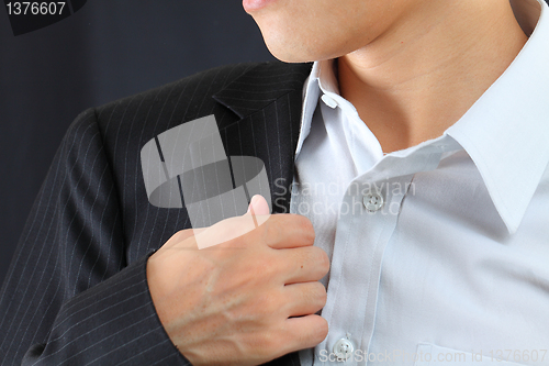 Image of young man adjusting his suit on a black background 