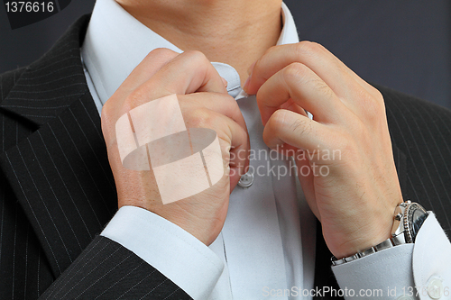 Image of young man adjusting his suit on a black background 