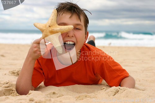 Image of Laughing boy with starfish on the beach