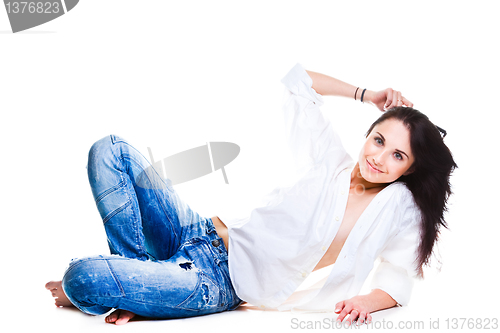 Image of sexy woman in blue jeans lying on white floor