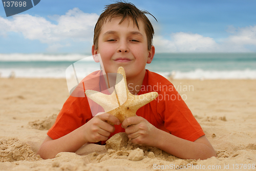 Image of Boy on beach holding a sea star