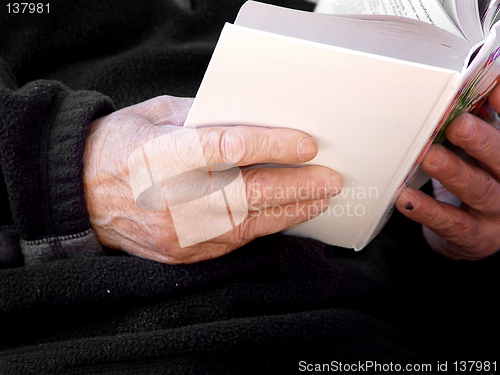 Image of Hands of an old man holding a book