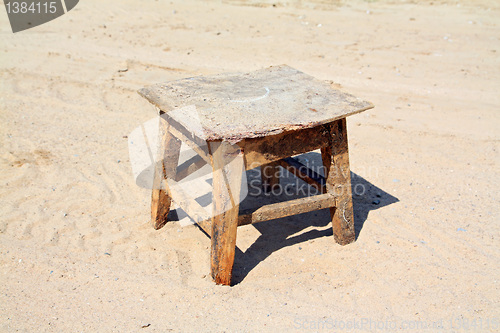 Image of old stool on sandy road