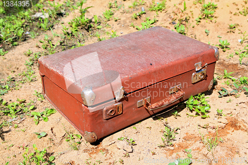 Image of old valise on yellow sand
