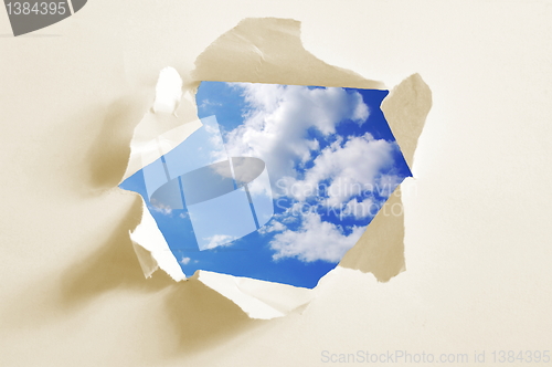 Image of cloudy sky behind paper hole