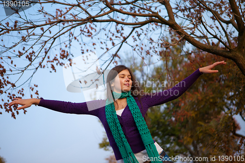 Image of Young girl with closed eyes and raised arms 