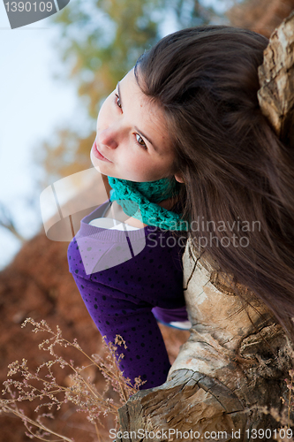 Image of Portrait of a young woman lying on log 