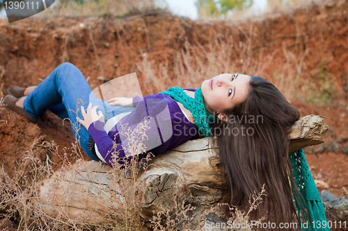 Image of Shot of a young woman lying on log 