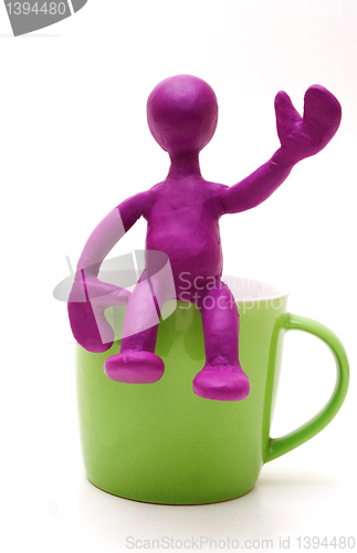 Image of Purple puppet of plasticine sitting on cup