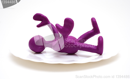 Image of Purple puppet of plasticine laying on plate