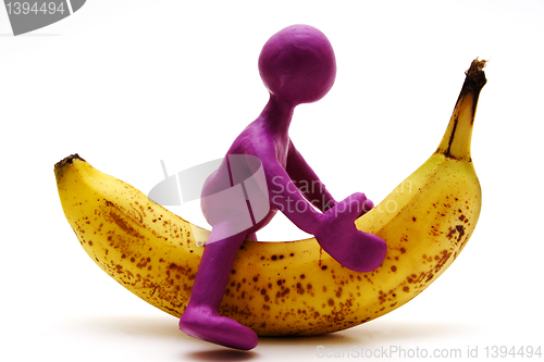 Image of Purple puppet of plasticine riding on banana